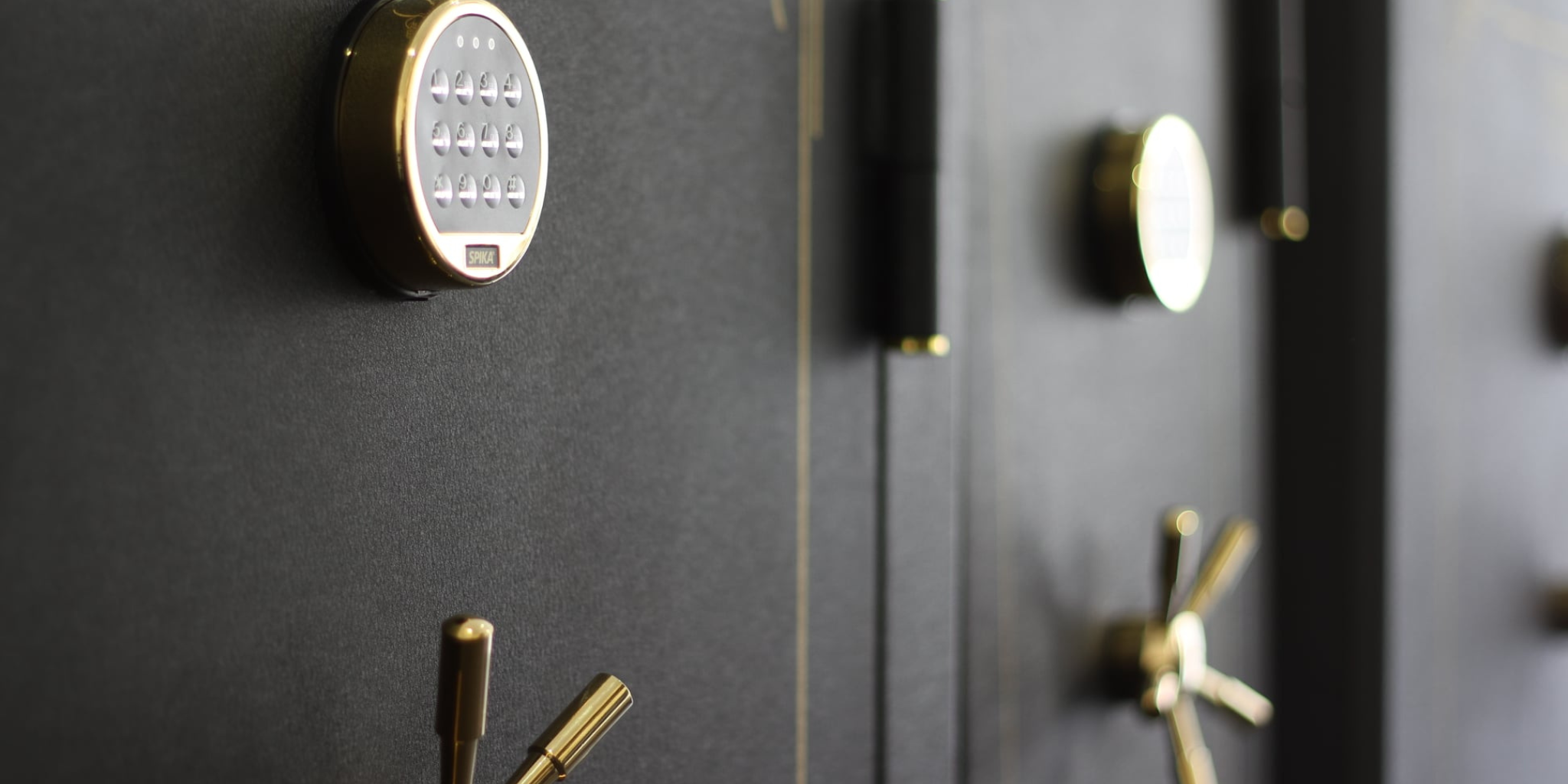 Close-up of a black gun safe with gold locks and keypad